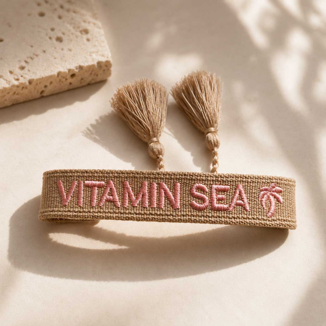 Vitamin Sea Statement Armband aufgeklappt mit beigen Quasten und Palmen-Stickerei – Flatlay, Saltyblush
