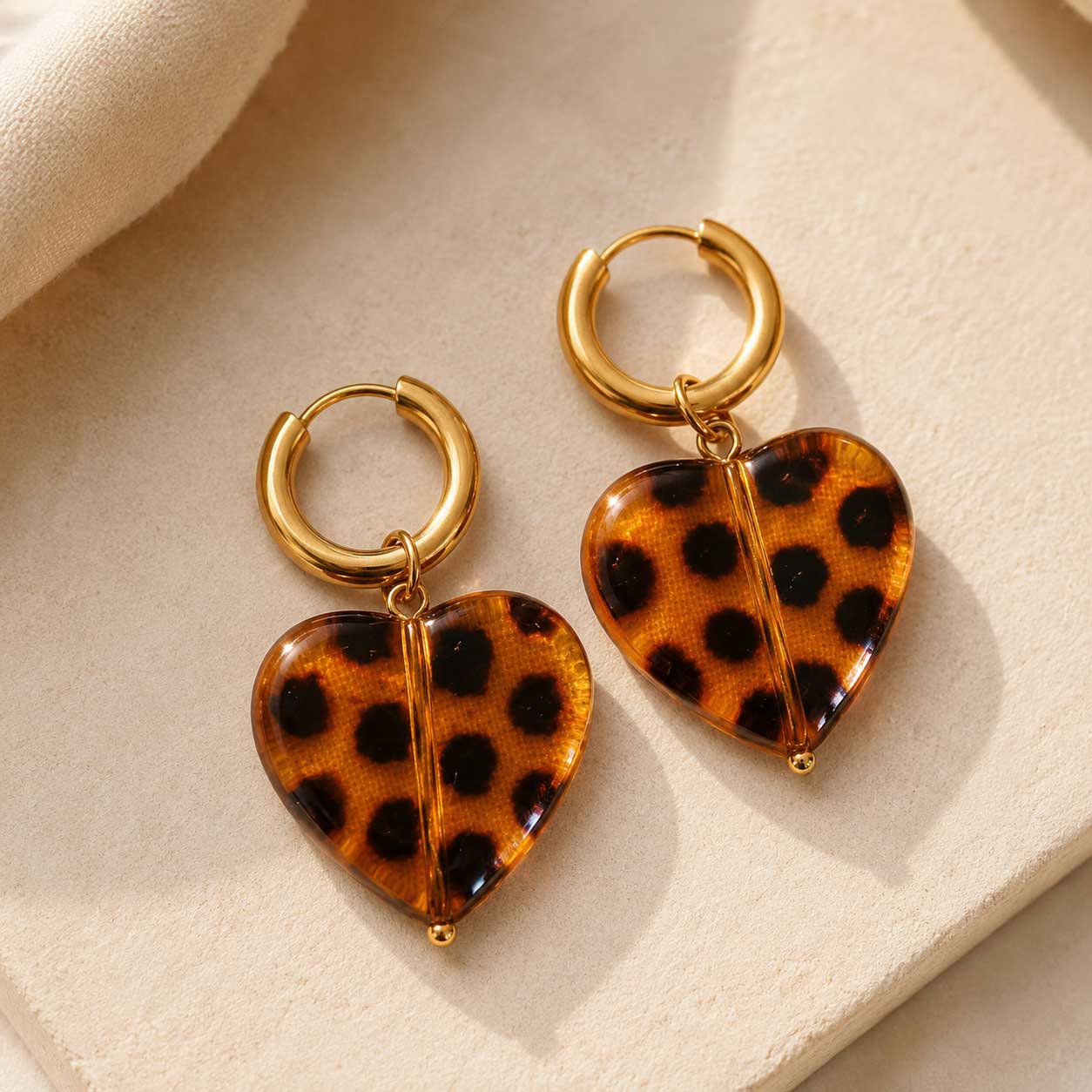 Goldene Creolen Wild Heart mit Leopardenherz-Anhänger aus Harz – Produktfoto auf beigem Hintergrund, Saltyblush
